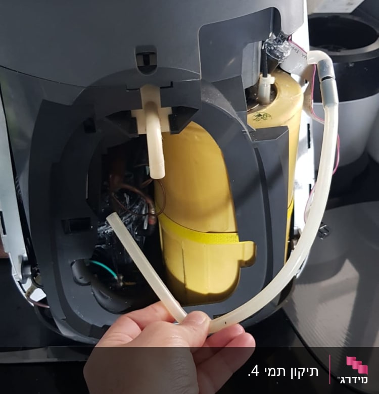 יד מחזיקה צינור פלסטיק במכשיר חשמלי פתוח